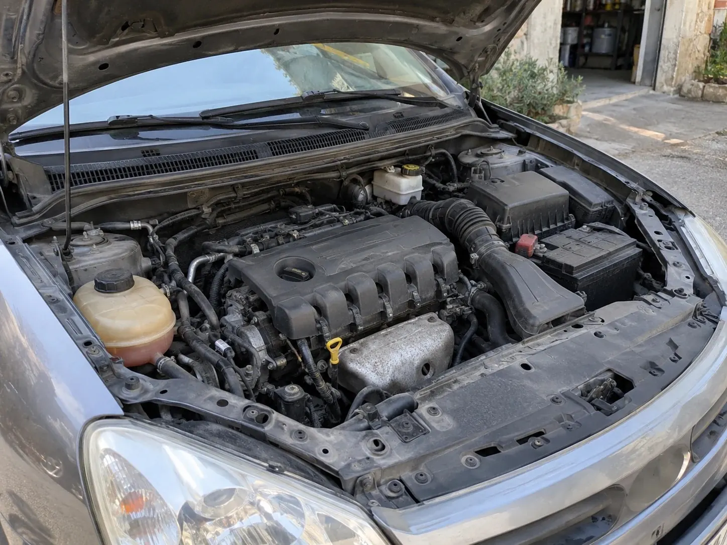Compartiment moteur d'une voiture grise, capot ouvert, moteur et équipements en place