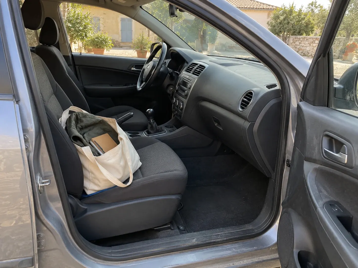 Habitacle d'une voiture, portière ouverte, sac posé sur le siège conducteur